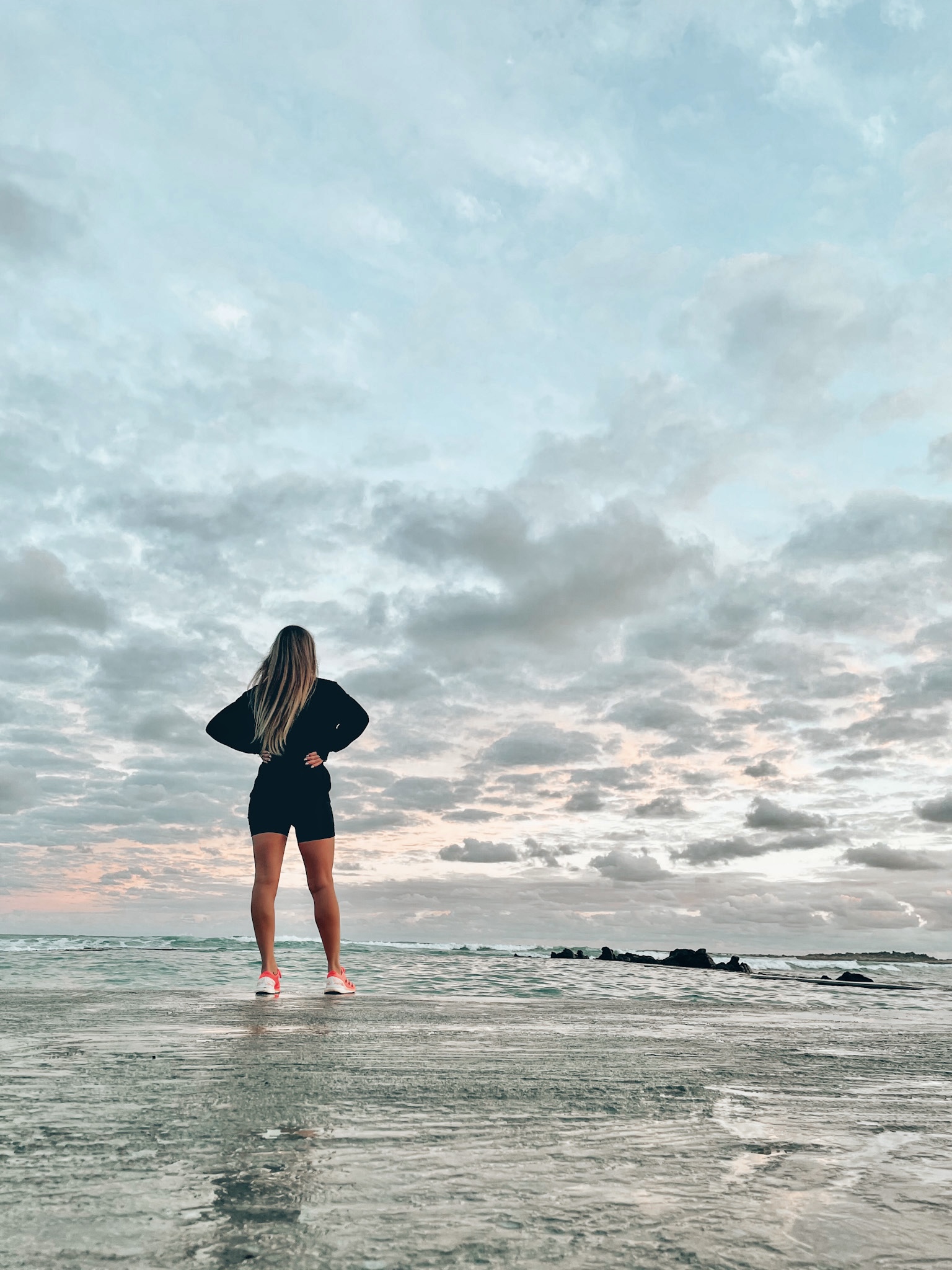 Woman standing at the ocean at sunrise